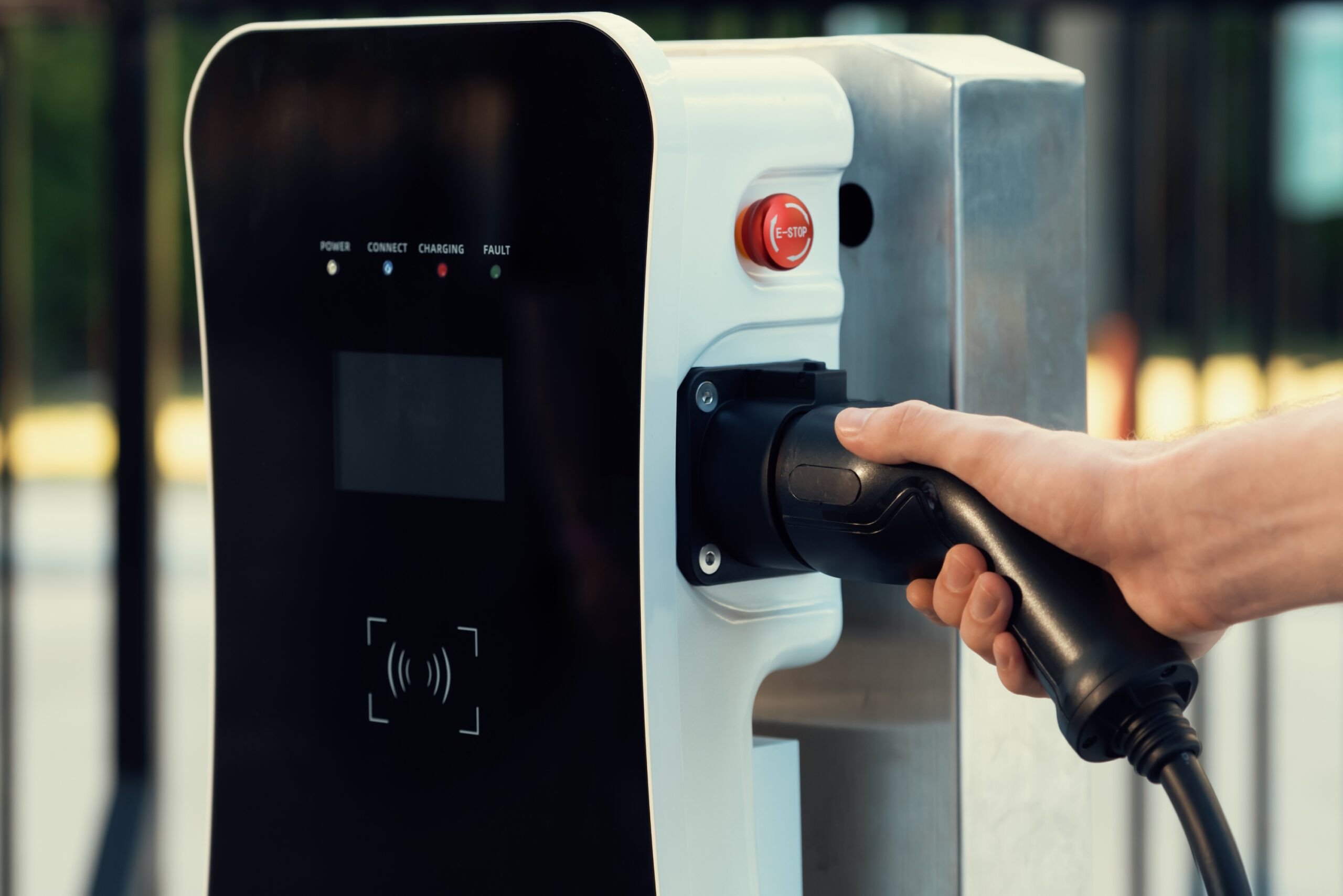 Closeup hand insert EV charger plug, green energy-powered charging point concept for EV car connected to progressive home charging station garage. Eco friendly rechargeable car.